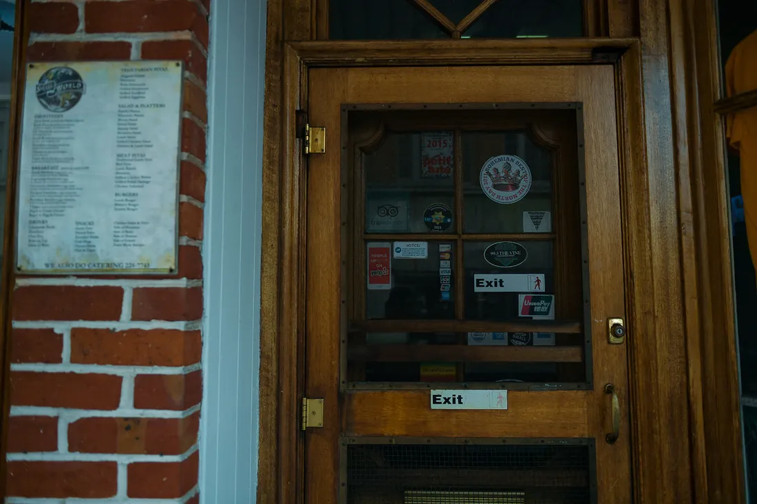 A shop door carrying a printed menu and a column of review-site and guidebook badges, the most recent dated several years ago.